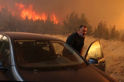 Un hombre abandona su vivienda ante la proximidad del fuego forestal en Dione, este lunes.