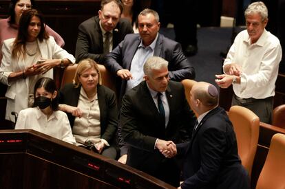 El ministro de Asuntos Exteriores israelí, Yair Lapid (segundo por la derecha) y el primer ministro saliente, Naftali Bennett, se estrechan la mano, este jueves en el Parlamento de Israel, en Jerusalén.