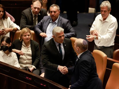 El ministro de Asuntos Exteriores israelí, Yair Lapid (segundo por la derecha) y el primer ministro saliente, Naftali Bennett, se estrechan la mano, este jueves en el Parlamento de Israel, en Jerusalén.