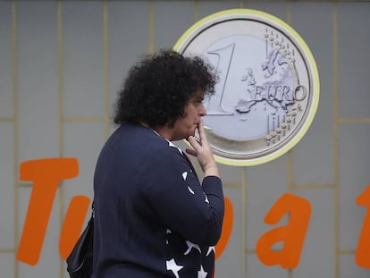 Una mujer fuma junto a un comercio de Lisboa.