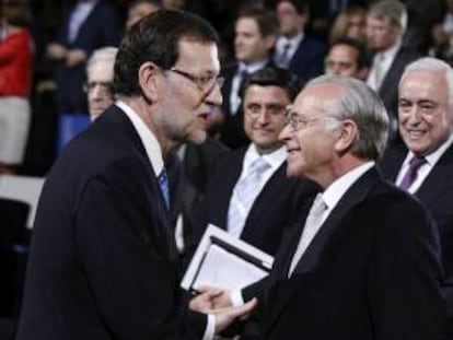 El presidente del Gobierno, Mariano Rajoy (i), que clausura la asamblea general de CEOE, celebrada hoy en Madrid, en la que se tratan cuestiones como el código de buen gobierno de la patronal que es la base para la reforma de sus estatutos, conversa con el presidente de La Caixa, Isidro Fainé.