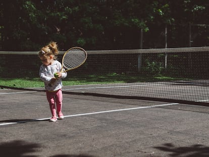 Una niña juega al tenis a pleno sol.
