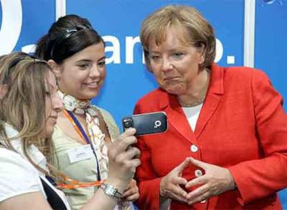 Dos estudiantes y Angela Merkel (derecha) observan un teléfono móvil durante un encuentro en Berlín dedicado al mercado laboral y las mujeres.