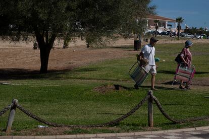 Una pareja atraviesa un parque con césped en Matalascañas, el pasado jueves.
