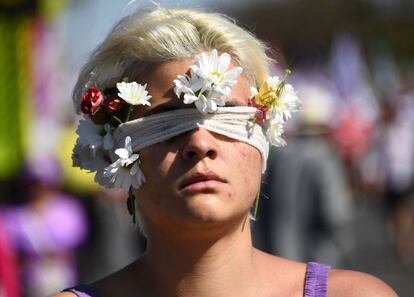 Una mujer participa en la marcha con el rostro cubierto de flores.