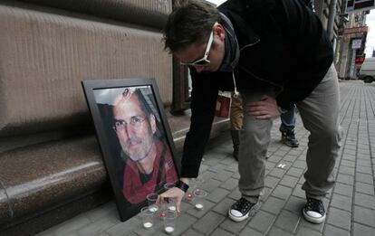 Un joven enciende una vela, como condolencia, en la tienda de Apple en Moscú