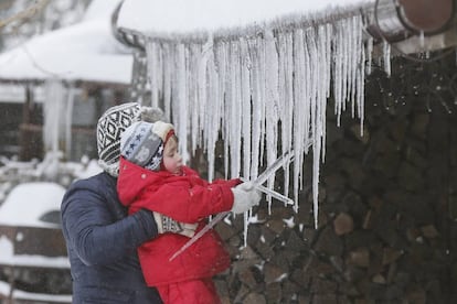 Una ni&ntilde;a juega con unas estalactitas de hielo. 