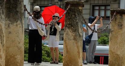 Unos turistas se fotografían el pasado martes junto al Archivo de Indias de Sevilla bajo la intensa ola de calor que mantiene en alerta a casi toda España.