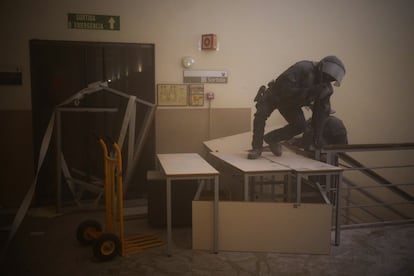 Un policía salta una barricada colocada en uno de los pasillos de la Universidad de Lleida. Al entrar los Mossos, los activistas se han refugiado en la tercera planta del edificio.