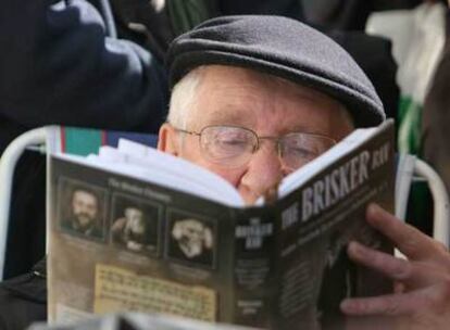 Un cliente de Northern Rock, hace cola sentado y leyendo un libro ante una oficina en Londres.