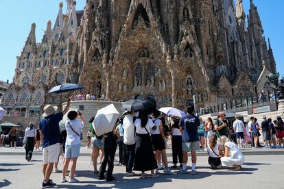 Varios turistas equipados con paraguas visitan la Sagrada Familia (Barcelona).