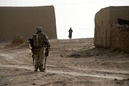 Un soldado estadounidense busca, con un detector de metales, posibles artefactos explosivos mientras un afgano lo observa en la localidad de Marjah.