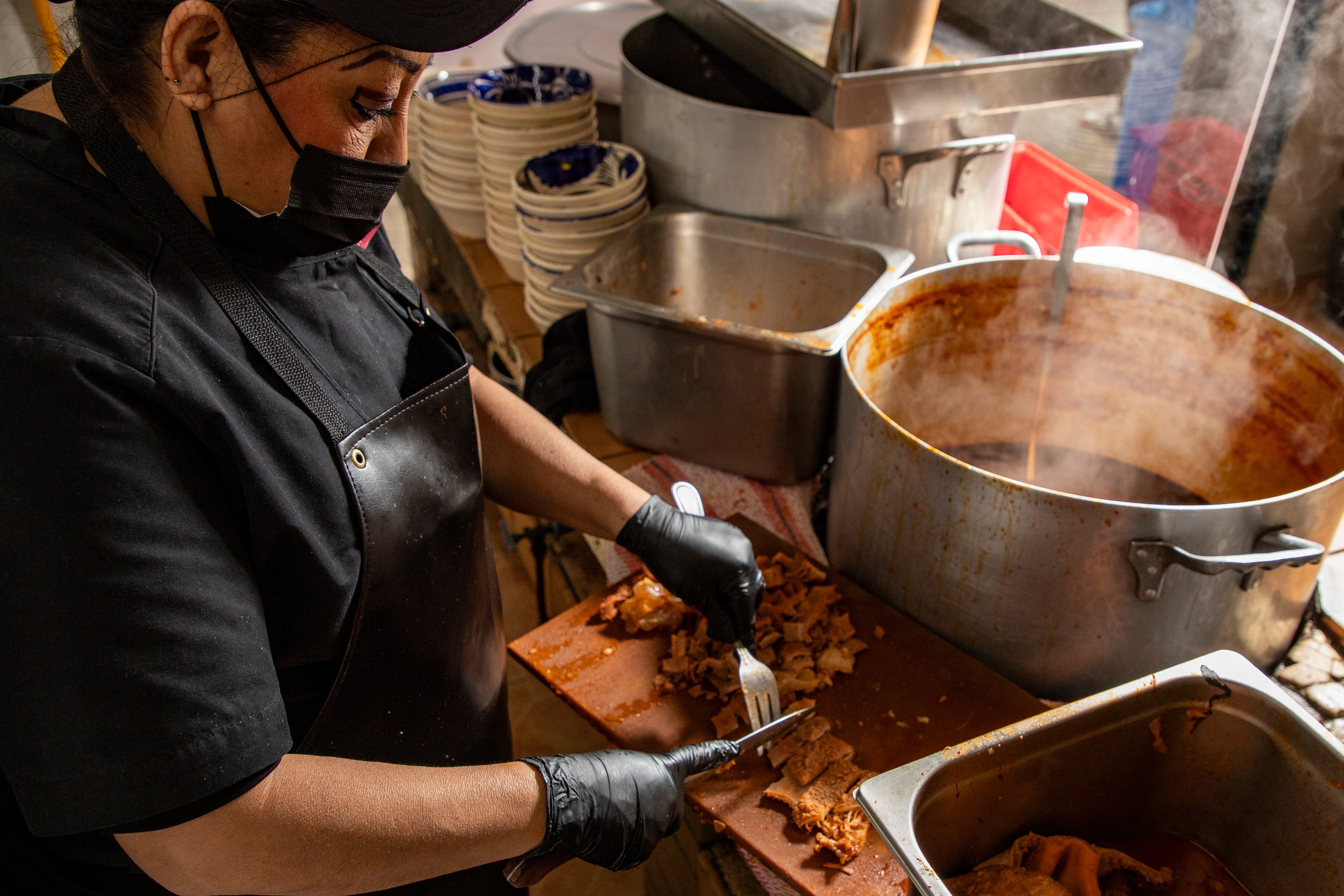 Una cocinera hace el corte de la pancita de res en La Pancita de la Roma.