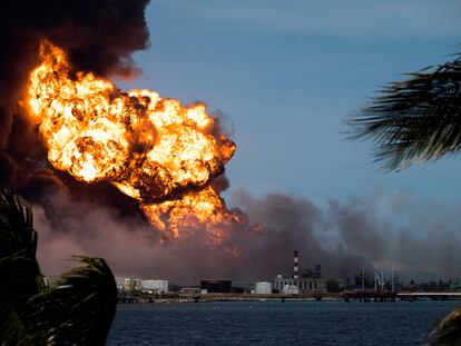 Flames rise from a massive fire at a fuel depot sparked by a lightning strike in Matanzas, Cuba, on August 8, 2022. - Cuban army helicopters scrambled to contain a blaze that felled a third tank at a fuel depot on Monday after burning for days, as the search continued for 16 missing firefighters. (Photo by YAMIL LAGE / AFP)