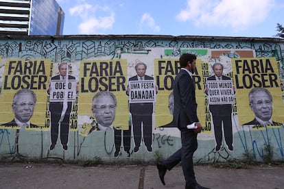 Homem passa diante de cartazes do ministro da Economia, Paulo Guedes, em São Paulo no dia 30 de agosto.