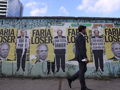 Homem passa diante de cartazes do ministro da Economia, Paulo Guedes, em São Paulo no dia 30 de agosto.