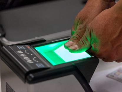 Una persona coloca sus pulgares en un escáner de huellas dactilares.