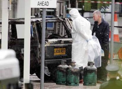 Dos policías examinan los restos del coche que se estrelló contra el aeropuerto de Glasgow. En primer plano, bombonas de gas que estaban en el vehículo.