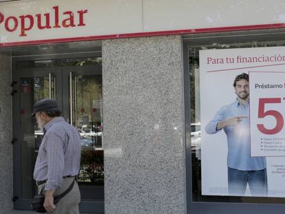 Un hombre pasa ante una oficina del Popular.