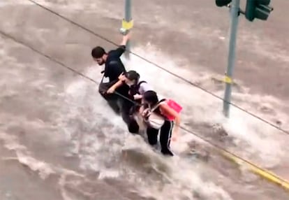 Tres personas intentan cruzar una calle inundada en Atenas (Grecia), este miércoles.