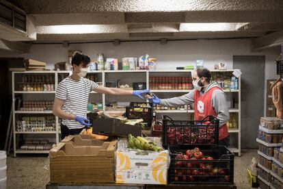 Dos voluntarios de la ONG De Veí a veí cargando cajas de alimentos para usuarios de la entidad.