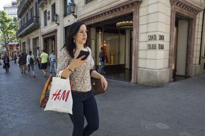 Una joven camina por el Paseo de Gr&agrave;cia, frente a la tienda de moda Santa Eulalia.