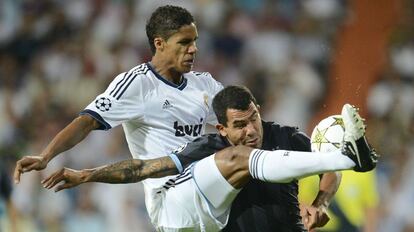 Carlos Tévez disputa el balón a Varane.