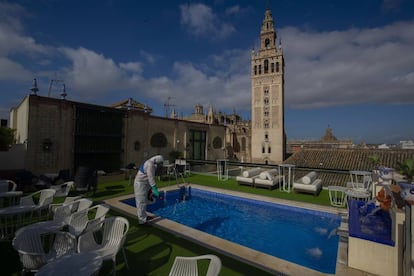 Un trabajador desinfecta la piscina con vistas a la Giralda del hotel Doña María, en Sevilla.