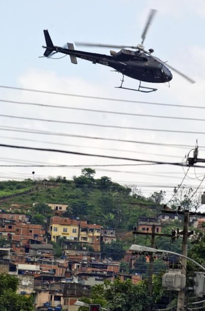 Un helicóptero de la Policía sobrevuela las favelas de la zona norte de Río de Janeiro, donde las fuerzas del orden mantienen desde el pasado domingo una batalla con los narcotraficantes. El Gobierno de Lula ha aprobado hoy el envío de 800 soldados y dos helicópteros militares para reforzar la operación.
