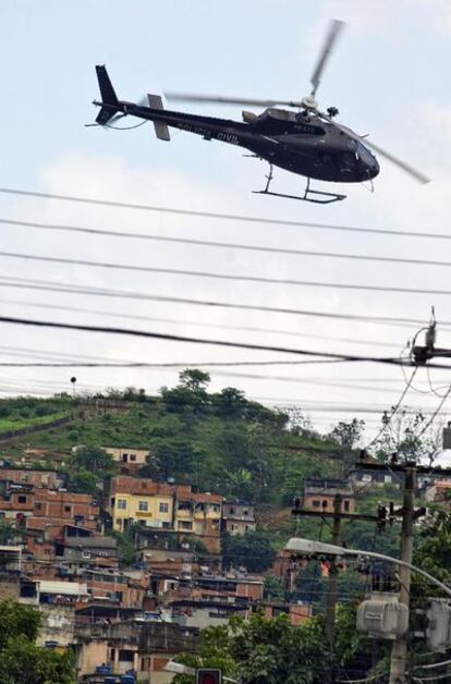 Un helicóptero de la Policía sobrevuela las favelas de la zona norte de Río de Janeiro, donde las fuerzas del orden mantienen desde el pasado domingo una batalla con los narcotraficantes. El Gobierno de Lula ha aprobado hoy el envío de 800 soldados y dos helicópteros militares para reforzar la operación.