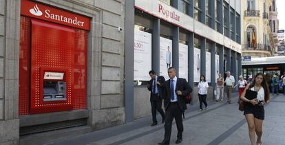 Transeúntes pasan delante de una sucursal del Santader y otra del Banco Popular