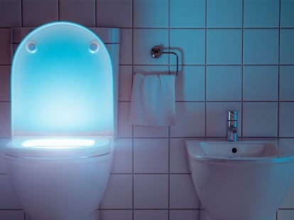 Un inodoro y un bidé iluminados por la noche en un cuarto de baño.