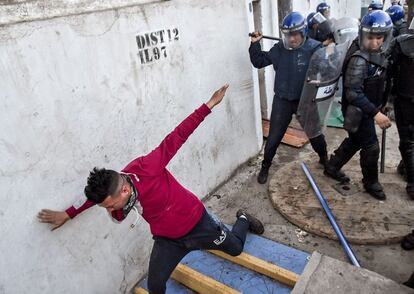 Un hombre trata de evitar ser golpeado por un miembro de las fuerzas de seguridad argelinas durante los enfrentamientos que se han producido en Argel.