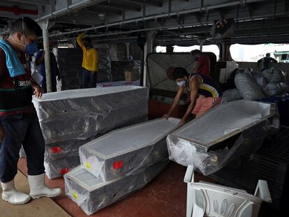 Varios trabajadores desembarcan ataudes llegados este viernes en barco a Manaos desde Santa Catarina (Brasil).