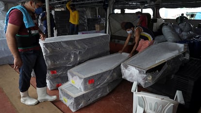 Varios trabajadores desembarcan ataudes llegados este viernes en barco a Manaos desde Santa Catarina (Brasil).