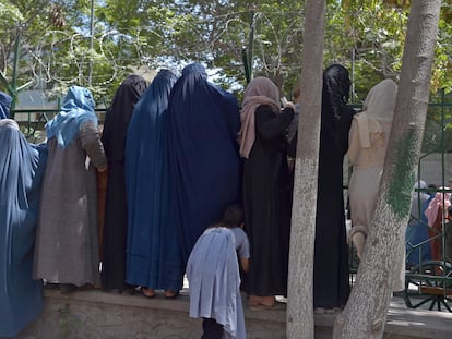 Mulheres afegãs que fugiram do avanço dos talibãs esperam para receber comida de ajuda humanitária em um parque de Cabul, na sexta-feira.