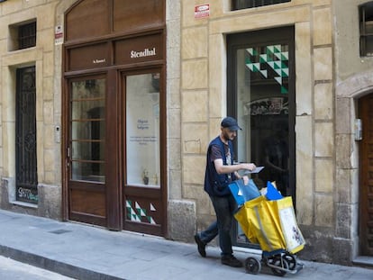 Un carter passa per davant d'un baix comercial en un carrer de Barcelona