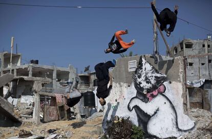 Palestinos practican 'parkour' sobre una pared derruida y pintada por el artista callejero Banksy, en la ciudad de Gaza.