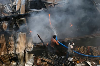 Varios hombres intentan sofocar las llamas de un incendio declarado en el centro comercial Randall Street de Monrovia (Liberia).