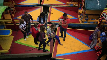 Turistas caminan entre trajineras en los canales de Xochimilco.