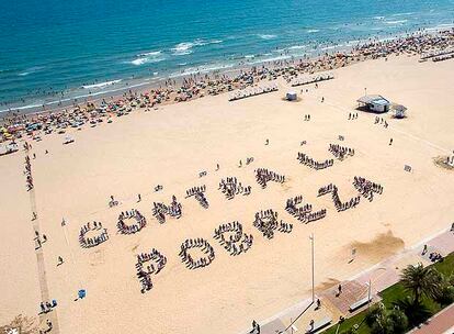 Centenares de personas se juntaron para formar el cartel humano, ayer por la mañana en la playa de Gandia.