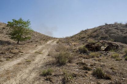 El esqueleto de un coche quemado cerca de La Cañada Real, donde se acumula basura a los lados del camino.