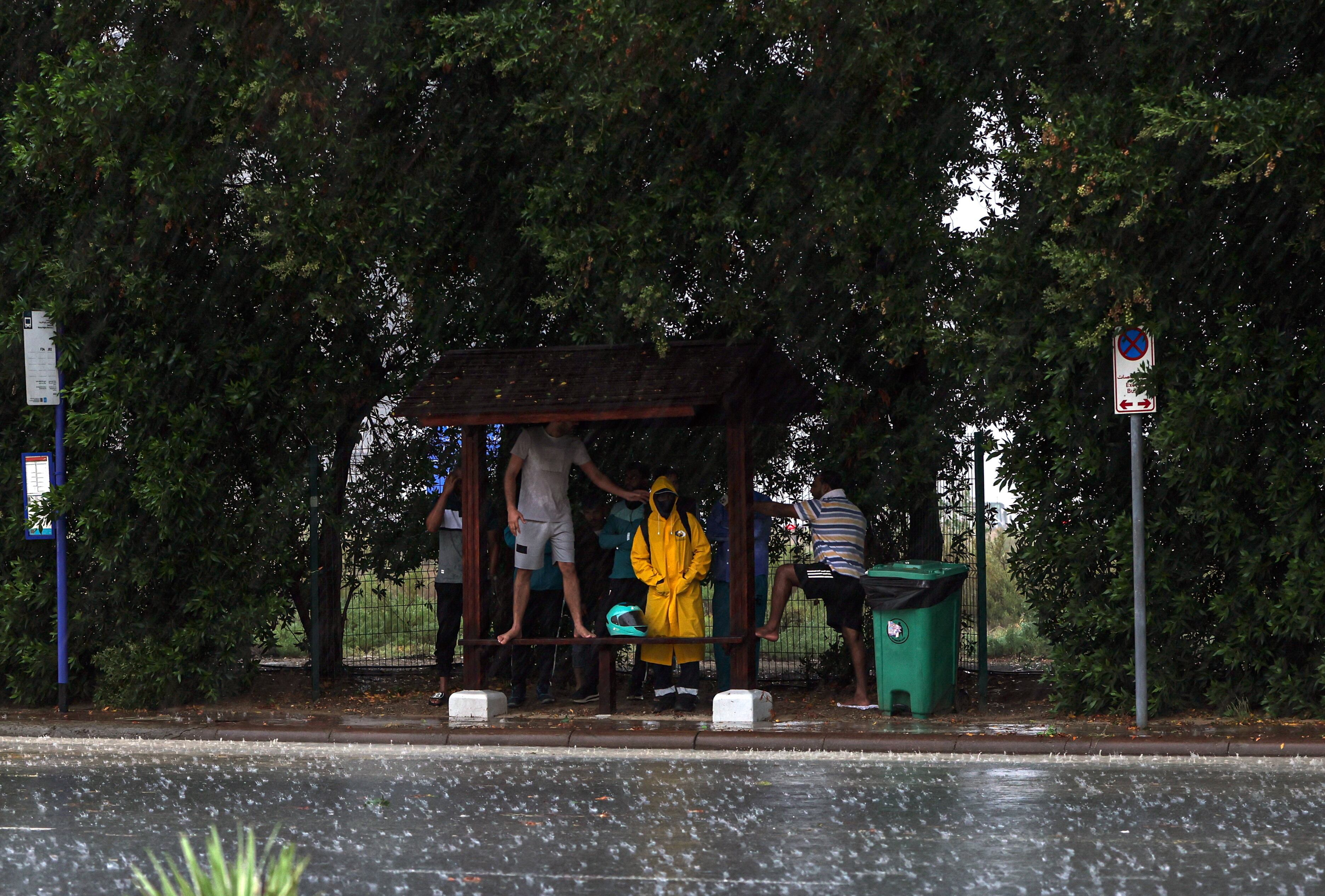 Varias personas se protegen de la lluvia, el martes en Dubái.