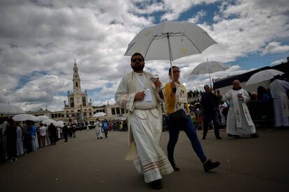 La Santa Comunión es entregada a fieles por sacerdotes bajo paraguas mientras el Papa Francisco conduce la misa en el Santuario de Nuestra Señora de Fátima, el 13 de mayo.