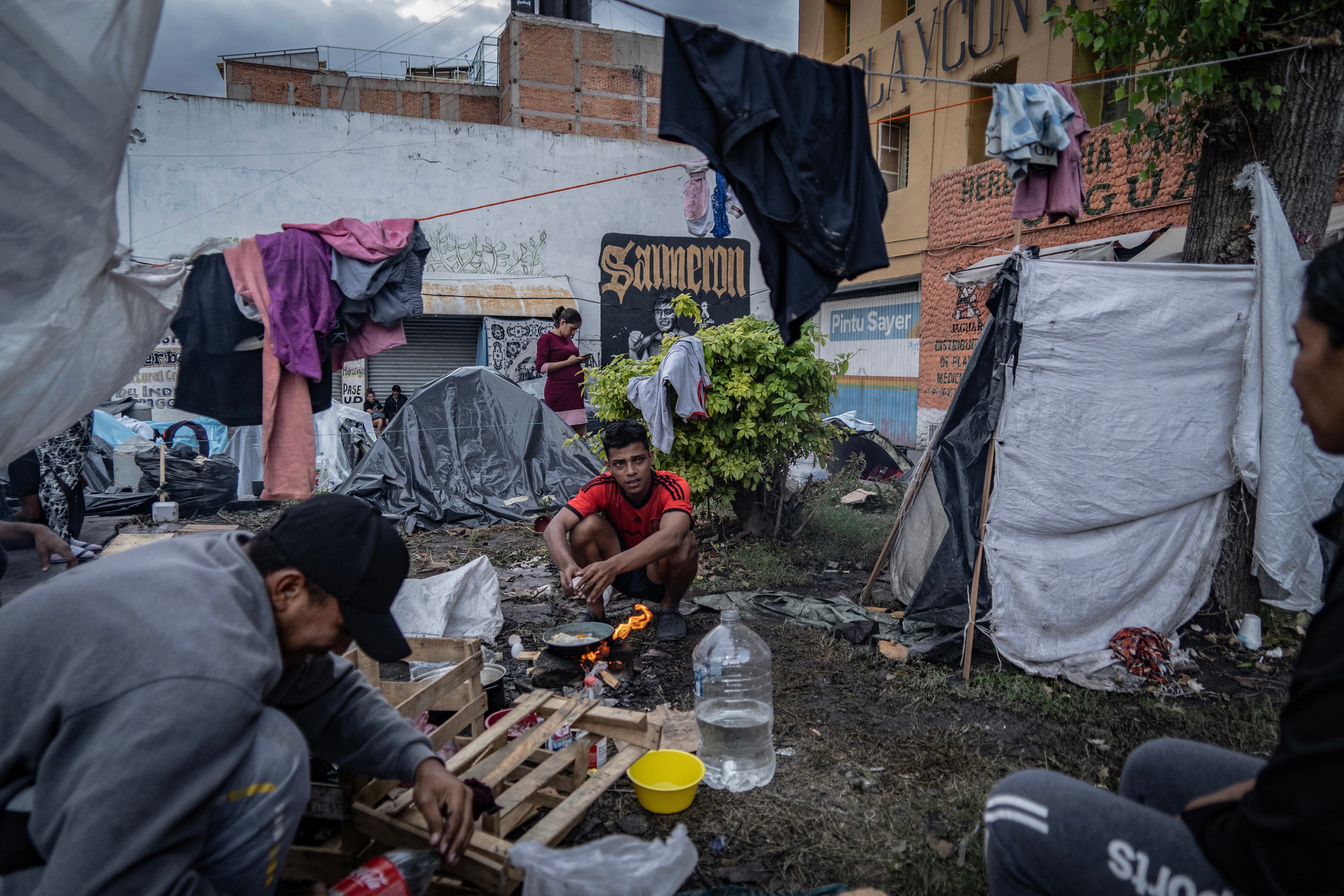 Dos migrantes cocinan su almuerzo en fogones improvisados, en el campamento ubicado a las afueras de La Soledad, el pasado 27 de octubre.