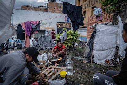 Two migrants cook their lunch on improvised stoves, in the camp located on the outskirts of La Soledad, on October 27, 2023.