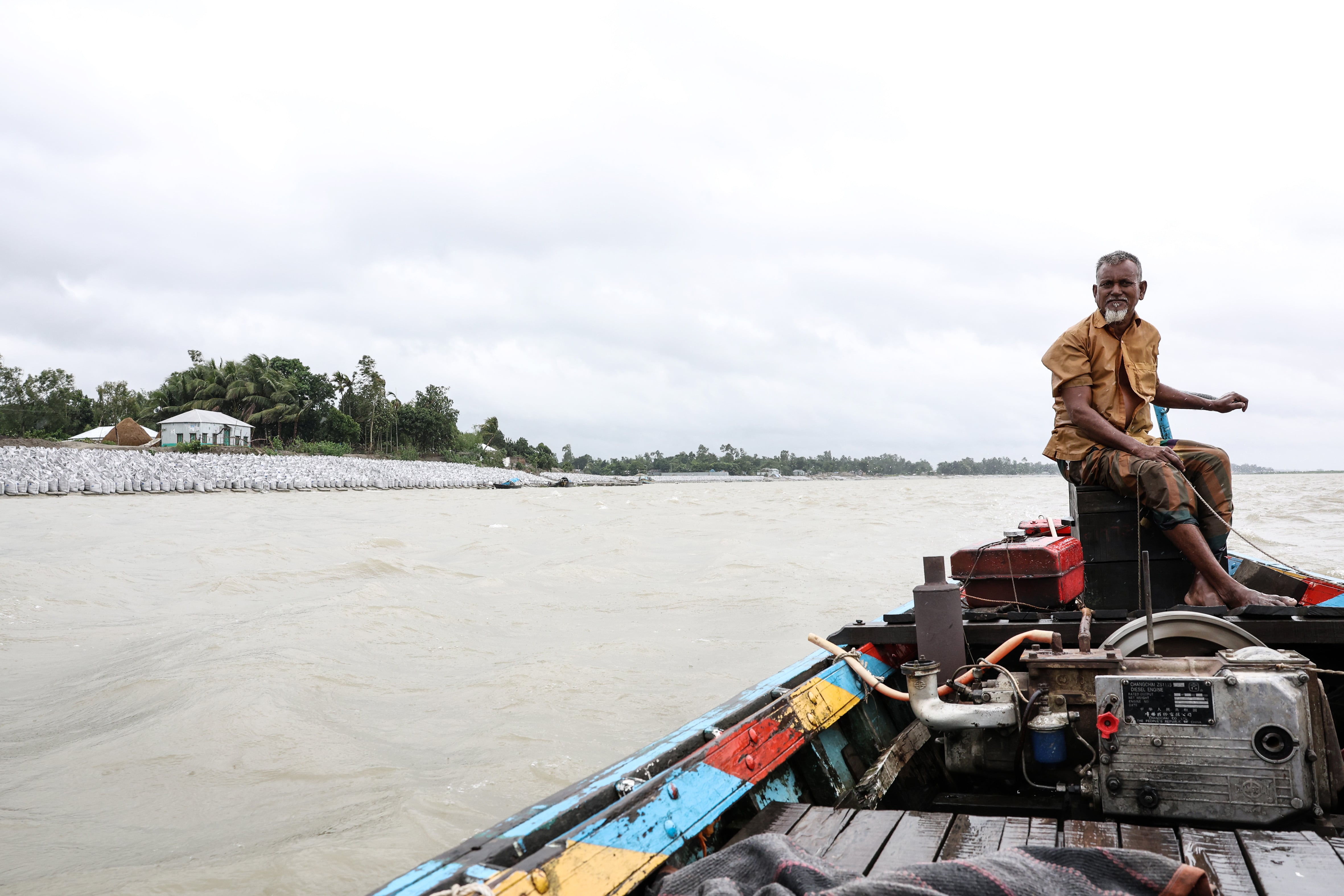 Ghulam Mustafa, de 70 años, navega entre sacos de arena en la orilla del río Yamuna en Sirajganj, Bangladés, el 29 de mayo de 2025.