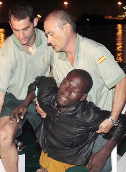Agentes de la Guardia Civil ayudan a uno de los inmigrantes que pasaron seis días en el mar.