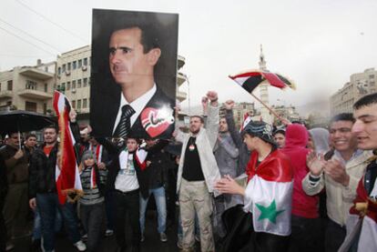 Simpatizantes del régimen de Bachar el Asad alzan su retrato en una manifestación en Damasco (Siria).