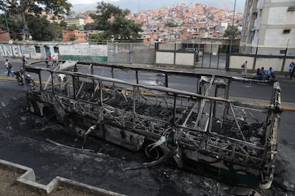 Vista de un autobús incendiado en la madrugada del martes al miércoles en la capital venezolana. Los disturbios en las protestas anteriores a la marcha han dejado al menos cuatro muertos, informa France Presse.